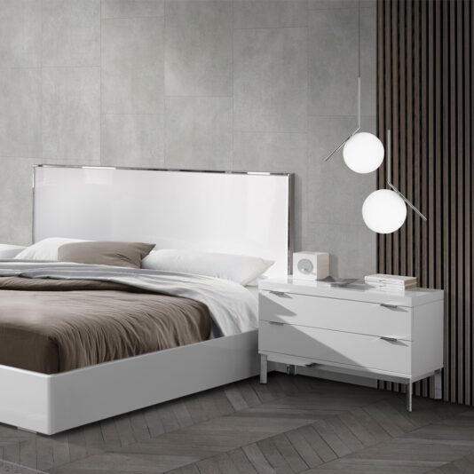 Deluxe Miami Style White Lacquered Bed Modern bedroom with a Deluxe Miami Style White Lacquered Bed, featuring a high-gloss headboard and neutral bedding. Beside the bed, a white nightstand holds a small speaker, stacked books, and geometric light fixtures with spherical bulbs hanging above. The room has a minimalist design.