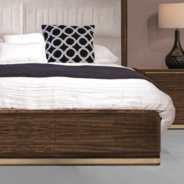 Contemporary Pleat Upholstered Bed A contemporary bedroom featuring the Contemporary Pleat Upholstered Bed with a wooden frame, pleat-upholstered white headboard, and matching bedspread. A black patterned pillow rests against the headboard. Beside the bed sits a dark bedside table holding a lamp with a beige shade and textured dark base.