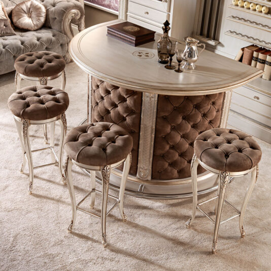 Luxury Italian Bar Stool A luxurious bar area with a tufted, upholstered counter featuring four matching Luxury Italian Bar Stools with elegant, cushioned seats. The counter is adorned with classic silverware and decorative items, set in a cozy, carpeted room. One of these exquisite Luxury Italian Bar Stools adds an extra touch of sophistication next to the plush sofa and shelves in the background.