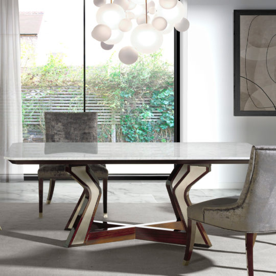 A modern dining room features a Luxury Marble Top Dining Table with a unique zigzag wooden base. Surrounding the table are three velvet-upholstered chairs. A cluster of spherical pendant lights hangs above the table, while large windows offer a view of greenery outside.