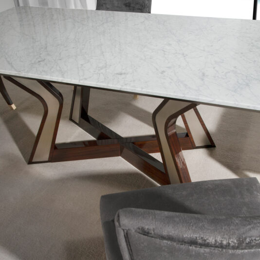 A rectangular marble table with a distinctive wooden and metallic base sits on a light-colored carpet, evocative of the Modern Walnut Console Table. A portion of a gray upholstered chair is visible in the foreground.