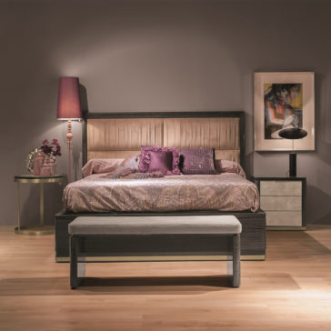 Luxury Modern Upholstered Bed A luxury modern bedroom features a Luxury Modern Upholstered Bed with a tufted headboard and purple bedding, accented with throw pillows. On either side, there are nightstands with a lamp and decor. A bench sits at the foot of the bed, and a colorful abstract painting hangs on the wall.