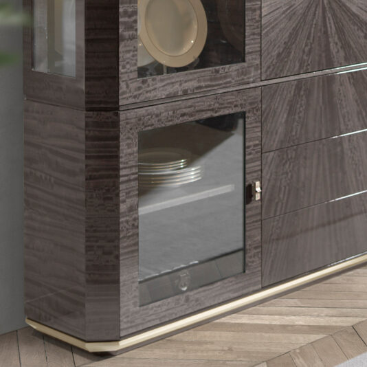 Luxury Modern Display Cabinet A close-up of the Luxury Modern Display Cabinet reveals its glossy, dark wood finish. The cabinet features glass doors showcasing plates within and sleek, horizontal lines. It stands on a light-colored base with a herringbone parquet floor in the background.