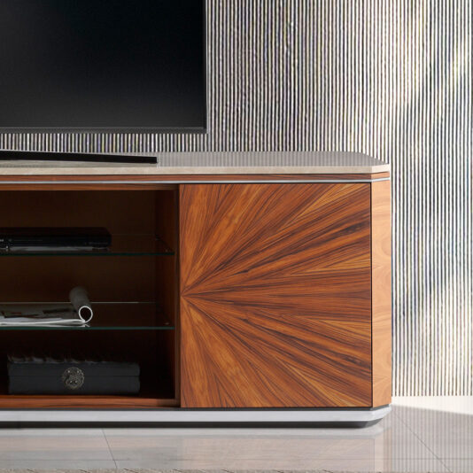 Luxury Modern TV Unit The Luxury Modern TV Unit features a wooden design with a geometric pattern on the cupboard doors. It includes a marble top and an open shelf divided by glass panels, holding a rolled-up white paper and a small box. A corner of a flat-screen TV is visible on top.