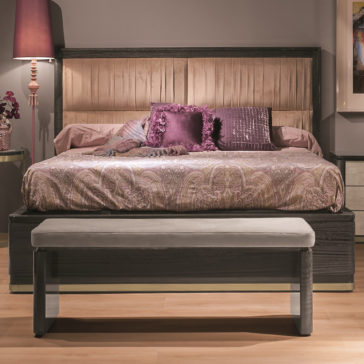 Luxury Modern Upholstered Bed A luxury modern bedroom features the Luxury Modern Upholstered Bed adorned with elegant, patterned bedding and decorative pillows. A cushioned bench is placed at the foot of the bed, while a bedside table with a lamp and a stylish arrangement enhances the serene ambiance.