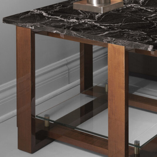 Modern Black Marble Top Side Table The Modern Black Marble Top Side Table features a stunning black marble surface adorned with white veining patterns, a wooden frame, and a glass shelf. The glass shelf is elegantly supported by four wooden legs with metal brackets. This stylish piece is showcased against a grey wall on a tiled floor.