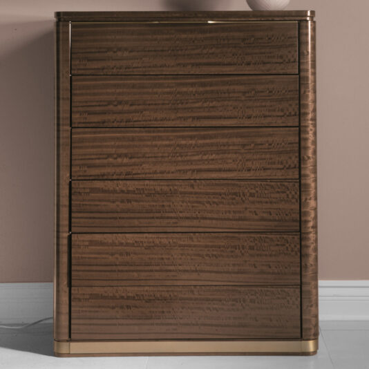 The Modern Tallboy Chest Of Drawers is a sophisticated piece, standing tall and crafted from wood with a sleek, glossy brown finish. It features five horizontal drawers, rounded edges, and rests gracefully on a light-colored floor against a muted pink wall. The drawer fronts highlight subtle, natural wood grain patterns.