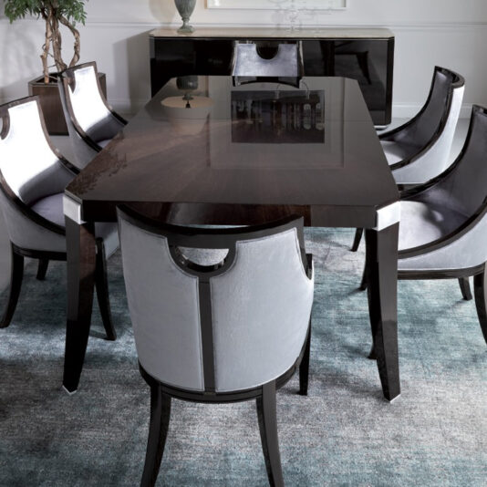 A sleek, modern dining room featuring the Modern Dark Walnut Dining Table with its polished edges. Around it, six chairs with light gray upholstery and black wooden frames. A matching black buffet is in the background, adorned with decorative items. A muted blue-gray rug ties everything together beautifully.
