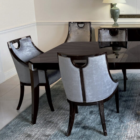 Modern Dark Walnut Dining Table A contemporary dining room showcasing the Modern Dark Walnut Dining Table with a glossy finish, surrounded by four chairs. The chairs feature dark wooden frames and are upholstered in light gray fabric. In the background, there is a stylish lamp and a decorative piece, accompanied by a modern rosewood sideboard and a blue rug underneath the table.