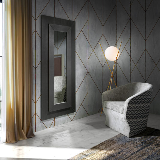 A modern, elegant interior features the Modern Elegant Armchair with a sleek gray design and zigzag patterned sides, alongside a tall rectangular mirror framed in thick black, a floor lamp boasting a round white shade on its tripod stand, and large windows adorned with beige curtains. The walls are designed with a geometric pattern that enhances the aesthetic.