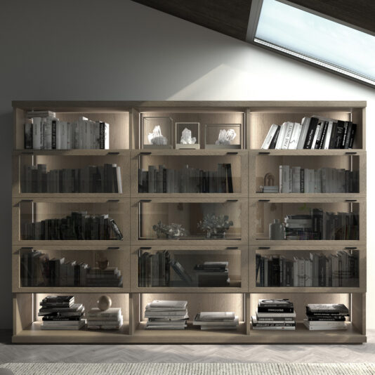A Modern Elegant Wooden Bookcase with integrated LED lighting sits under a skylight, showcasing various books and decorative items. The bookcase features three columns, each with four glass-fronted compartments. Soft lighting accentuates the objects, creating a sophisticated ambiance.