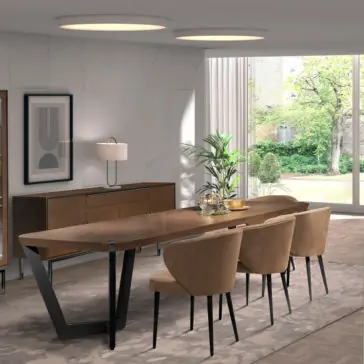 Modern Luxury Dining Set The room is graced by the Modern Luxury Dining Set, which includes a contemporary wooden table with a sleek black metal base and six chic beige upholstered chairs. Against the wall stands an elegant buffet console complemented by a stylish lamp and framed artwork. Large windows provide a view of the lush green garden, flooding the space with natural light.