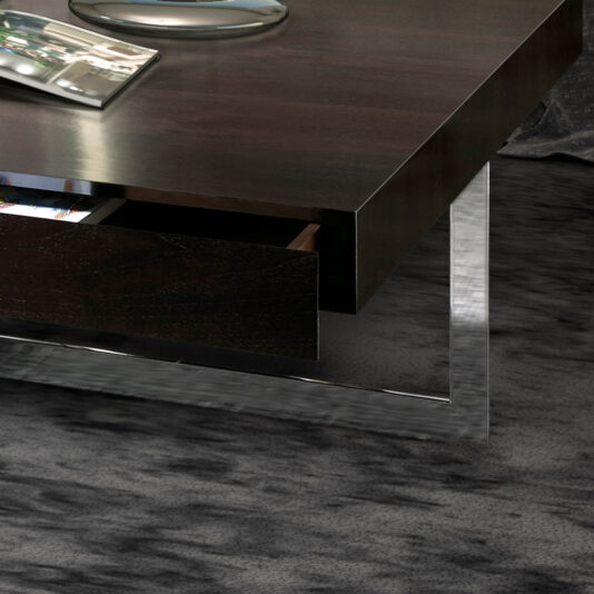 A Modern Square Coffee Table With Drawers, featuring dark wood and a metal frame, graces a textured gray carpet. A sleek, curved silver object sits elegantly on the table's surface.