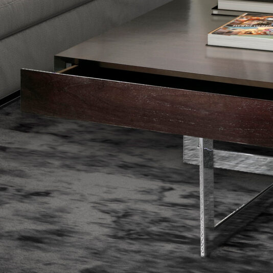 The Modern Square Coffee Table With Drawers showcases a dark wooden drawer that is partially open, highlighting its sleek design. The table stands on metallic legs and is placed on a textured grey carpet, with a few books stacked neatly on top.
