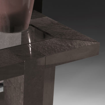 Modern Square Side Table With Glass Top Close-up of the Modern Square Side Table With Glass Top. The table boasts a sleek, glossy surface with a dark finish and features a geometric design characterized by sharp edges and clean lines. Part of a reflective vase is visible on the glass top. The background transitions from dark to light gray in a gradient pattern.