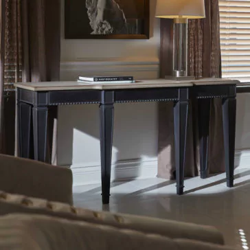 A sophisticated Modern Two-Tone Wooden Console Table with black legs and a light-colored tabletop is placed against a wall. On the table, there is a single book titled 