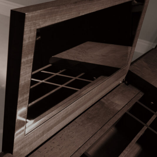 The Modern Vanity With Brass Accents is depicted in a sepia-toned photo, showcasing its open lid that reveals an interior mirror along with various compartments for organizing jewelry. This wooden jewelry box boasts a smooth finish and classic design, featuring multiple storage sections reminiscent of contemporary styling.