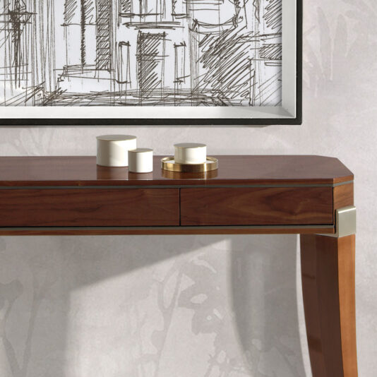 A Modern Walnut Console Table with sleek, tapered legs and a minimalist design stands against a light-colored wall. On the table are four cylindrical containers in varying sizes, some white and others metallic. Above the table hangs a framed abstract cityscape sketch.