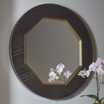 Modern Wooden Octagonal Mirror The Modern Wooden Octagonal Mirror showcases a gold-colored inner frame. Reflected in the mirror is a part of the wall along with some light-colored orchids in bloom, artfully placed on the lower right side.