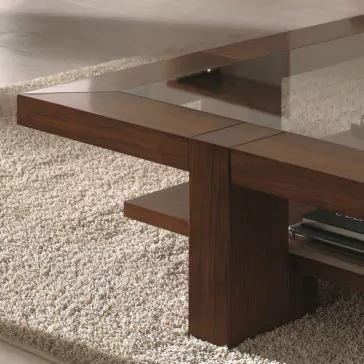 The Wooden Square Coffee Table With Glass Top sits on a light-colored textured rug. This modern table features clean lines and a lower shelf beneath the glass surface.