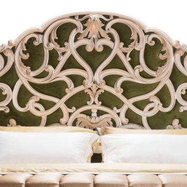 Carved Rococo Style Bed With Tall Headboard The Carved Rococo Style Bed With Tall Headboard showcases exquisite scrollwork designs set against a dark green velvet backdrop, accompanied by a neatly made bed adorned with light-colored bedding and pillows.