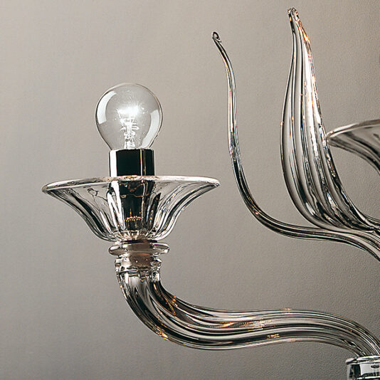 Classic Clear Glass Ribbed Detail Wall Light A close-up of the Classic Clear Glass Ribbed Detail Wall Light, showcasing its modern elegance with curved arms and a single clear light bulb. The ribbed glass elements reflect light beautifully, imparting a contemporary and sophisticated appearance against a neutral wall.