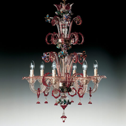 The Classic Glass Chandelier With Red Floral Detailing is a lavish masterpiece featuring intricate designs and an elegant combination of pink and red hues. It boasts six upward-facing light bulbs symmetrically arranged, adorned with colorful red floral detailing, and complemented by hanging crystal ornaments, all set against a dark background.