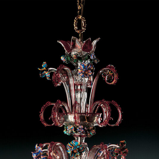 A detailed close-up of the Classic Glass Chandelier With Red Floral Detailing reveals intricate blue designs and gold accents, set against a dark background. The craftsmanship showcases swirling patterns and delicate, colorful flowers, making it a stunning centerpiece.