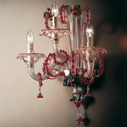 The Classic Glass Wall Light With Red Floral Detailing is an ornate, wall-mounted glass sconce featuring three elaborate arms, each holding a candle-shaped light bulb. The intricate design showcases fish-scale-like patterns and vibrant decorative flower elements, reflecting a luxurious style.