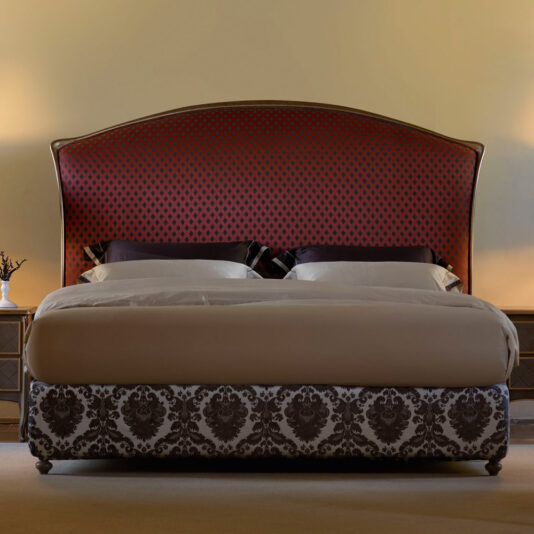 A luxurious Classic Italian Bed with a tall, curved headboard featuring a red and black pattern is centered in the frame. Its base showcases an elegant brown and white damask pattern. Two pillows are arranged on the bed, which is made with neatly tucked beige and white bedding.