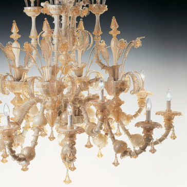 Large Classic Murano Glass Chandelier The Large Classic Murano Glass Chandelier is a detailed and ornate piece made of delicate Murano glass and gold. It features multiple arms with candle-like lights, exhibiting intricate designs and floral motifs that create an elegant and luxurious appearance against a gradient background.