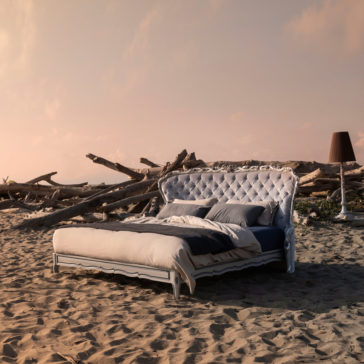 Classic Style Button Upholstered Winged Bed The Classic Style Button Upholstered Winged Bed, featuring a luxurious white tufted headboard, is positioned on a sandy beach amidst driftwood under a pinkish sky. The bed is neatly made with white and dark-toned bedding, while a tall, dark standing lamp blends into the serene beachfront setting.