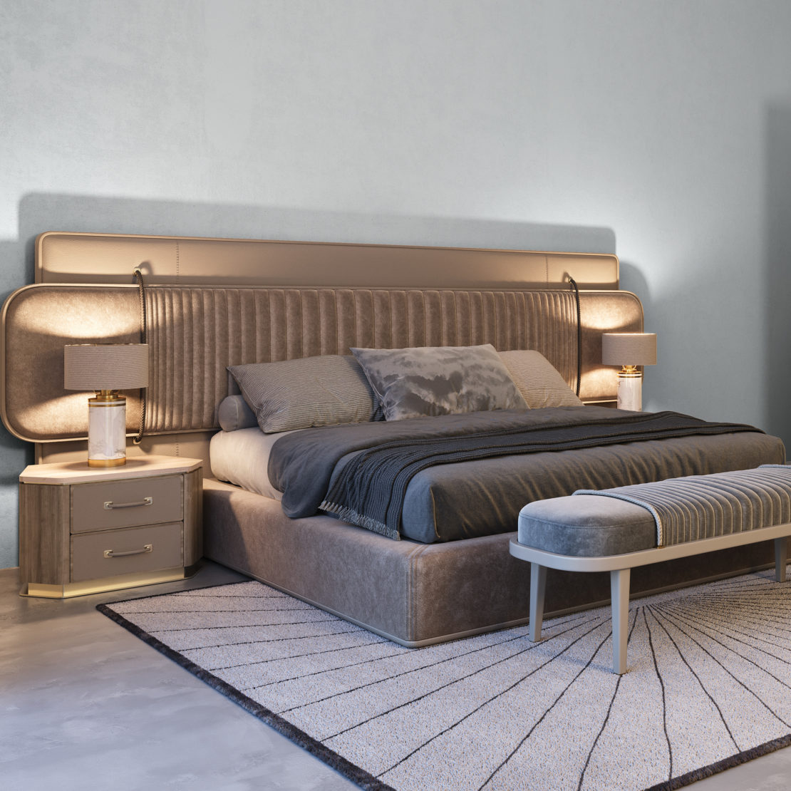 A contemporary bedroom showcasing the luxurious High-End Ribbed Detail Bed, which features a padded headboard, multiple pillows, and a grey quilt. The room also includes matching bedside tables with lamps, a cushioned bench at the foot of the bed, and a beige area rug with a geometric pattern.