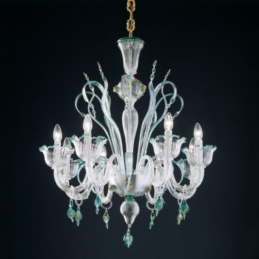 The Elegant Chandelier With Teal Detailing is suspended from the ceiling, showcasing an intricate glass design. It features multiple curved arms, each holding a light bulb covered by a flower-shaped glass shade adorned with green and gold accents against a dark background.