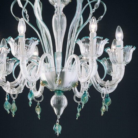 The **Elegant Chandelier With Teal Detailing** showcases a refined design with numerous intricately crafted arms, each holding a light bulb. This chandelier is adorned with delicate glass accents featuring leaf and flower shapes highlighted by subtle hints of teal green. Set against a dark background, the chandelier's radiant luminosity stands out beautifully.