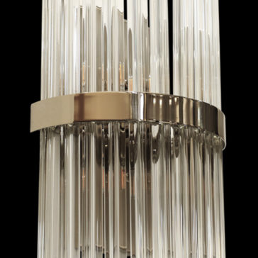 Luxury Glass Wall Light With Brass Trim A close-up of the Luxury Glass Wall Light With Brass Trim showcases its modern chandelier design, featuring vertical crystal rods and a metallic ring encircling the center. The elegant structure includes clear crystal columns that refract light beautifully, creating a luxurious and sophisticated appearance against the black background.