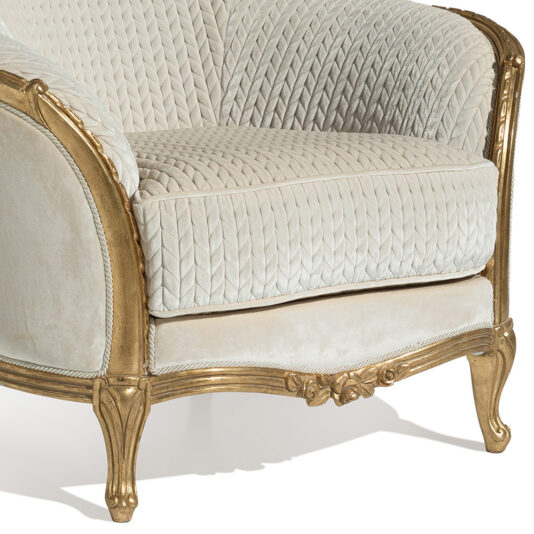 Luxury Venetian Style Armchair Behold the Luxury Venetian Style Armchair in close-up: featuring an exquisitely carved, golden wooden frame, luxurious textured cream-colored fabric upholstery with quilted patterns on the backrest and seat cushion for a plush and elegant look.