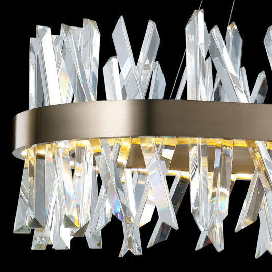 Oval Crystal And Brass Chandelier The Oval Crystal And Brass Chandelier features a sleek brushed metal frame in an elegant oval shape, ornamented with an array of elongated, clear glass crystals that cast a gentle, warm glow. The intricately arranged crystals sparkle at various angles, set against a black background for a sophisticated and modern look.