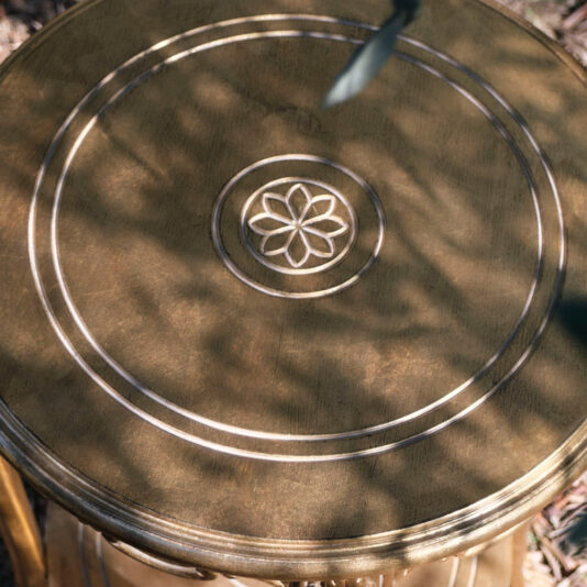 Rococo Style Round Gold Bedside Table A Rococo Style Round Gold Bedside Table with intricate carvings, featuring concentric circles and a central floral-like pattern. The tabletop catches dappled sunlight, creating a blend of light and shadow.
