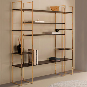 The Stylish Brass And Wood Bookcase, featuring a modern open shelving design, is displayed against a beige wall. The gold metal frame perfectly complements the dark wooden shelves, which are adorned with various items such as books, decorative objects, and a small plant. A patterned rug can be seen partially on the floor.