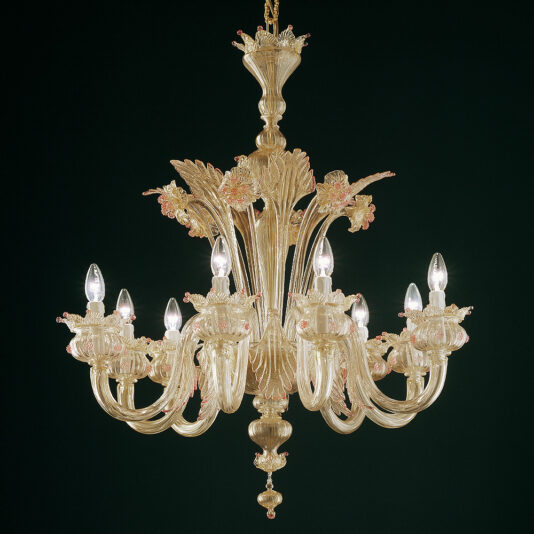 The Gold Glass Chandelier With Nature Inspired Details is a lavish piece made of ornate, clear glass adorned with delicate pink flower accents. It features twelve elegantly curved arms, each holding a candle-like light bulb, set against a deep green background. Intricate glasswork designs further enhance its opulence.