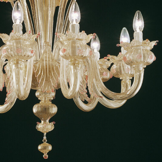 A close-up photo of the Gold Glass Chandelier With Nature Inspired Details, showcasing its multiple glass arms adorned with candle-shaped light bulbs. The chandelier features intricate designs, including leaf and flower motifs in gold and pink hues, elegantly set against a dark background.