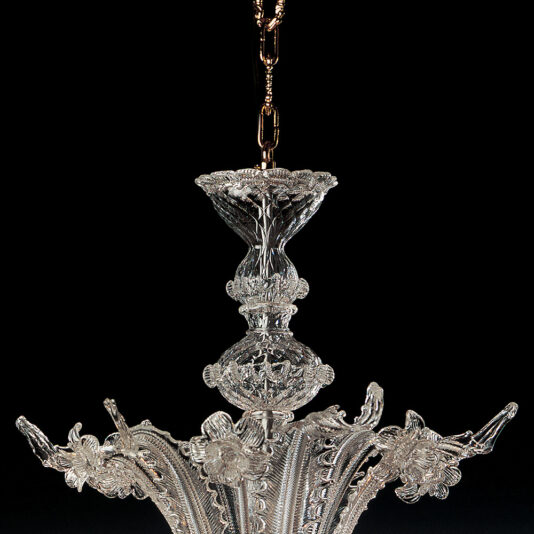 Classic Floral Clear Glass Chandelier A close-up of the Classic Floral Clear Glass Chandelier, showcasing its ornate crystal features with intricate floral motifs. Suspended from a chain, this chandelier boasts elaborate clear glass work with detailed patterns and textures, all highlighted against a dark background.