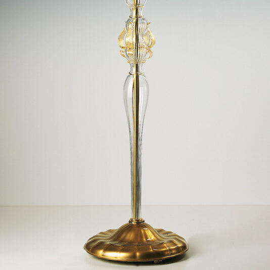 The Classic Floral Gold Glass Floor Lamp boasts an ornate, transparent glass body adorned with golden highlights and a decorative flourish near the top. Its rich, polished gold base features a gently ridged design, standing gracefully on a plain white background.