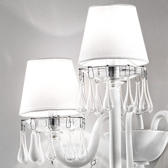 Classic Glass Teardrop Accent Wall Light With Three Arms The image showcases a close-up of two modern white lampshades featuring decorative clear glass teardrop pendants encircling the edges. These lamps, mounted on white bases against a plain light-colored wall, exude a minimalistic and elegant aesthetic reminiscent of the Classic Glass Teardrop Accent Wall Light With Three Arms.