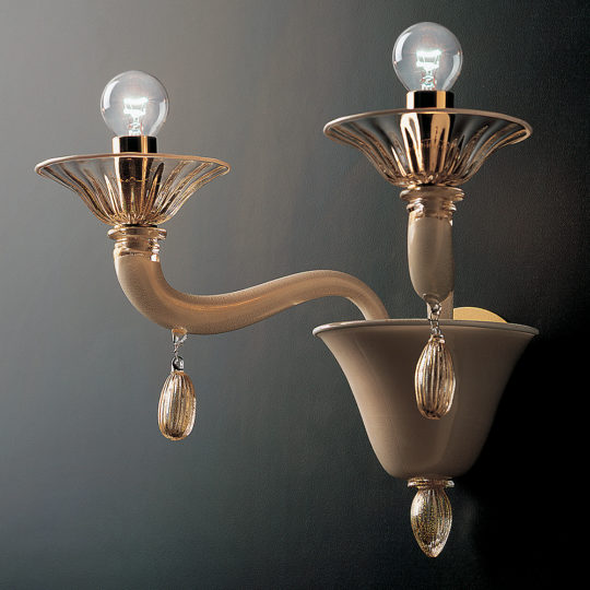 The Classic Gold Glass Wall Light With Gold Frame features a decorative sconce with two curved arms, each holding a light bulb with a clear, fluted glass shade. The fixture boasts gold accents and teardrop-shaped ornaments beneath the bulbs, all elegantly attached to a dark background.