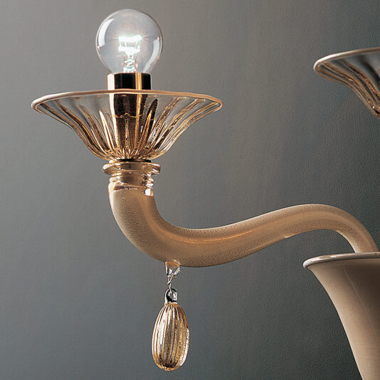 Classic Gold Glass Wall Light With Gold Frame A close-up of the Classic Gold Glass Wall Light With Gold Frame, featuring a vintage-style design with a curved beige arm, a translucent decorative sconce, and a clear light bulb. Below the sconce hangs a small ornamental charm. The background is a gradient of light to dark gray.