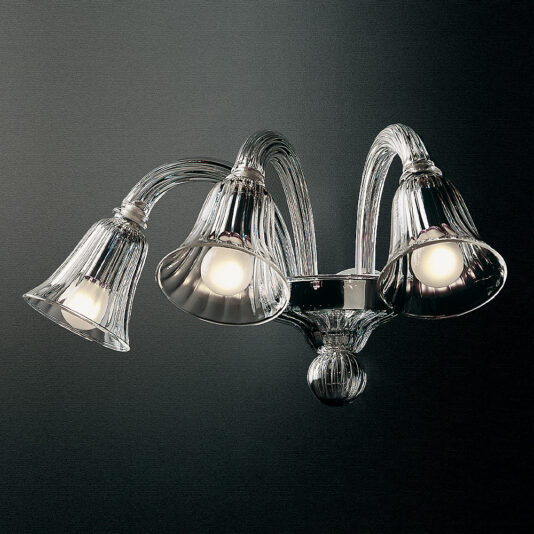The Clear Ribbed Detail Glass Wall Light is a decorative wall-mounted fixture featuring three elegant glass shades with intricate ribbed detailing. Each shade houses a light bulb, and the fixture's arms curve gracefully upward and outward, offering a sophisticated and modern look against a dark background.