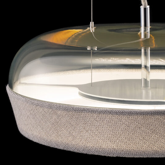Contemporary Dome Glass Pendant Light The Contemporary Dome Glass Pendant Light features a cylindrical glass dome with a glossy, reflective surface and an inner metal section. This modern pendant light is suspended by a thin cable, adorned with a fabric band that gracefully wraps around the lower part of the dome.
