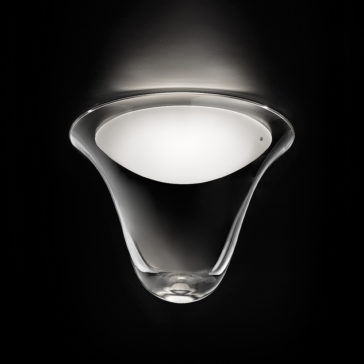 A modern, cone-shaped wall sconce with a smooth, white inner surface emits a soft, ambient light upwards. Reminiscent of the Contemporary Frosted Glass Ceiling Light, the fixture is set against a dark background, highlighting its sleek, glossy design and gentle curves.